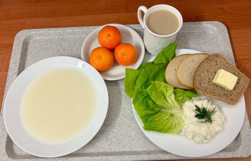 Na zdjęciu znajduje się: Kasza manna na mleku, Kawa zbożowa z mlekiem, Chleb mieszany pszenno-żytni, Chleb graha, Masło extra 82%, Twarożek, Sałata zielona, Mandarynka